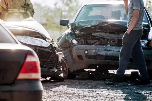 A driver walking up to his car after an accident involving multiple vehicles on the road.