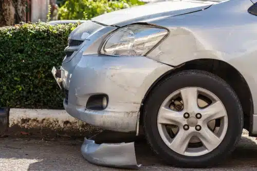 A parked car with damage to its front end after an accident with another vehicle.