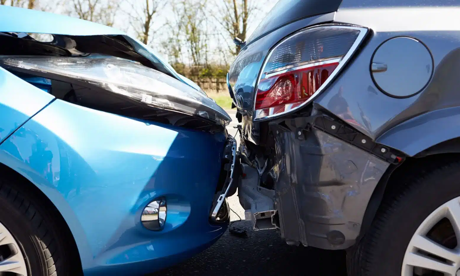 A closeup of a rear-end collision between one blue vehicle and one black one.