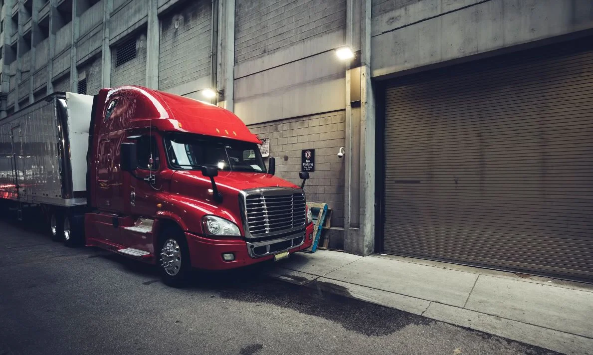 A brand new semi truck approaching a warehouse after a long drive.