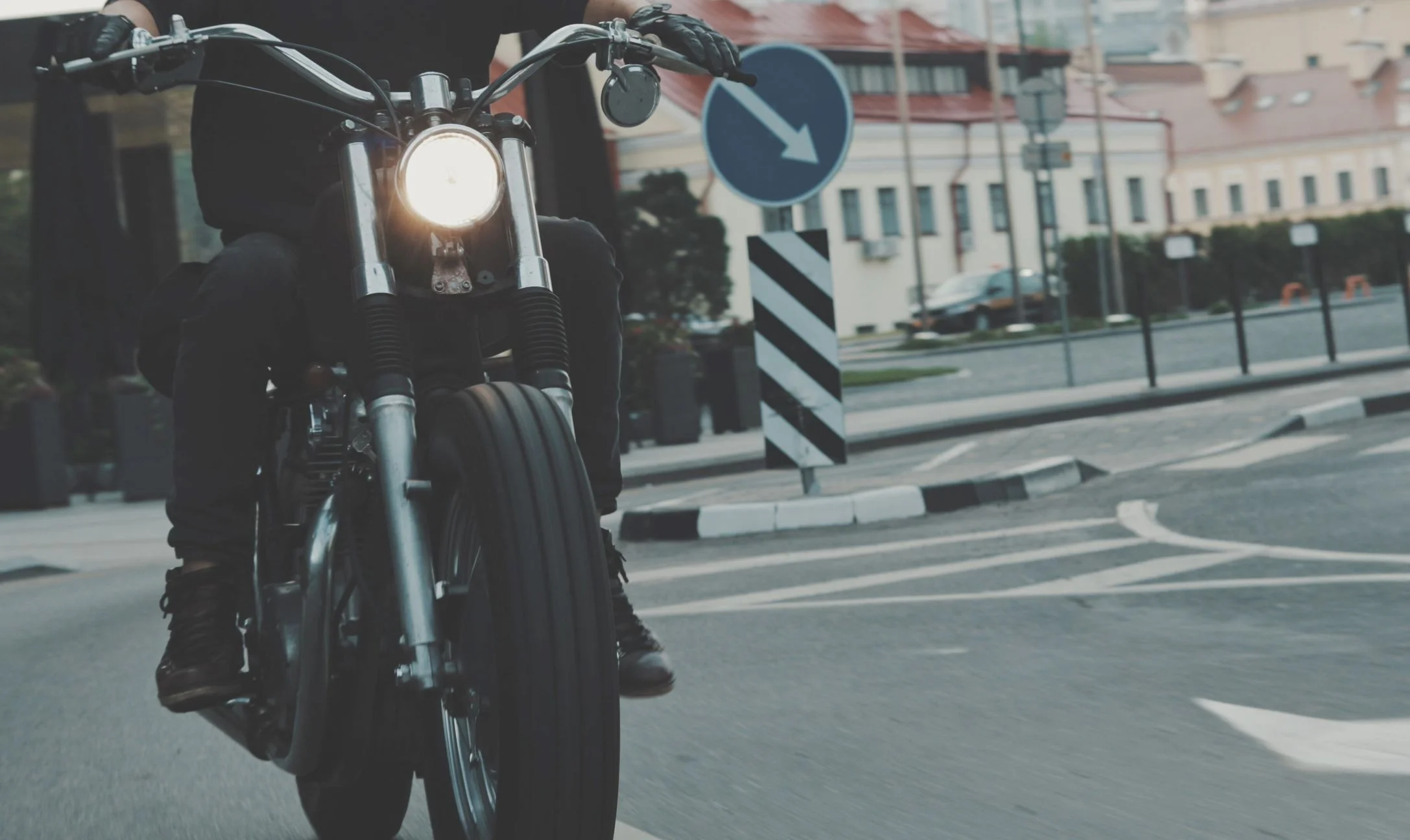 A motorcycle going down a city road in the early evening.