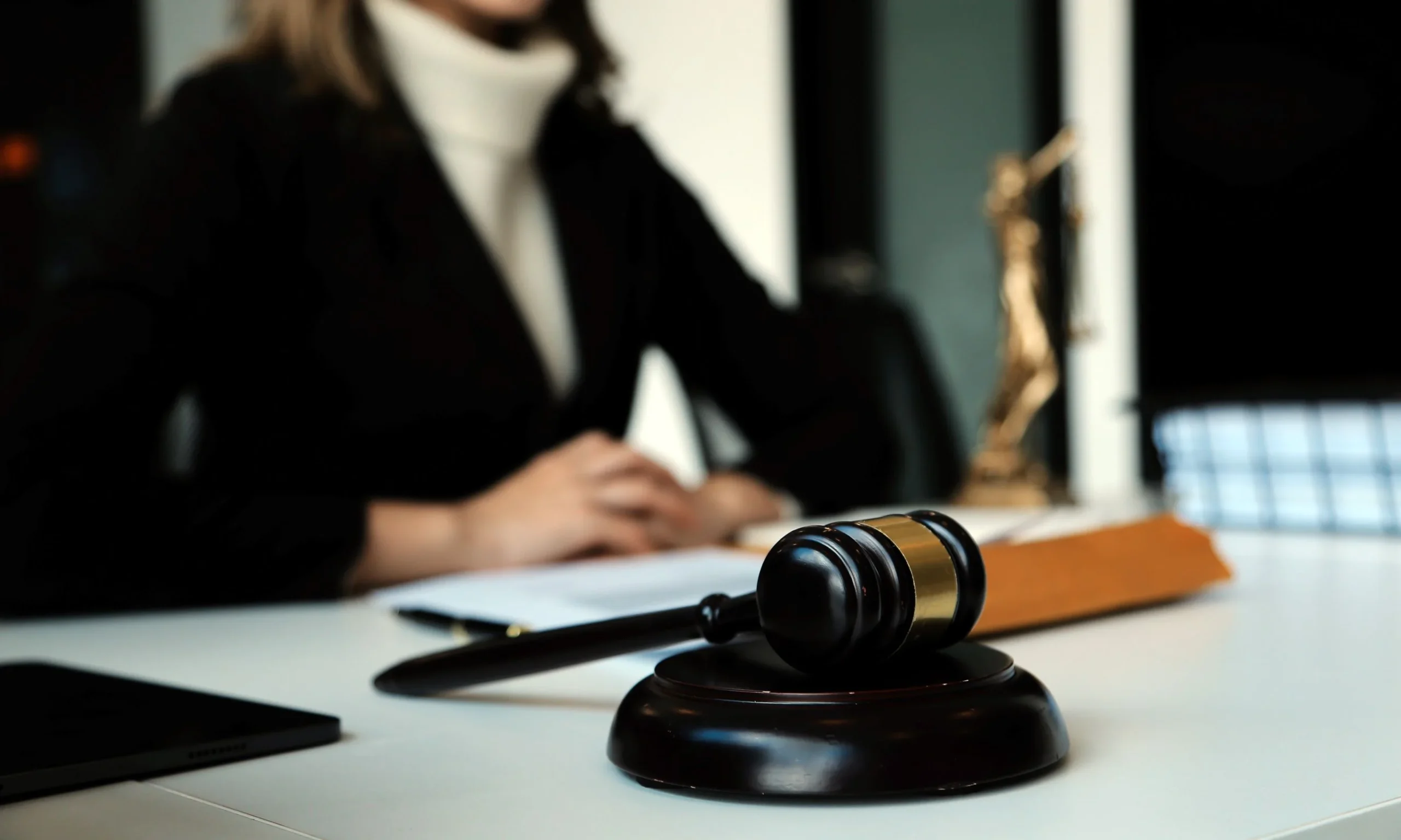 A depth of field shot of a wrongful death lawyer in her office with a gavel in the foreground.