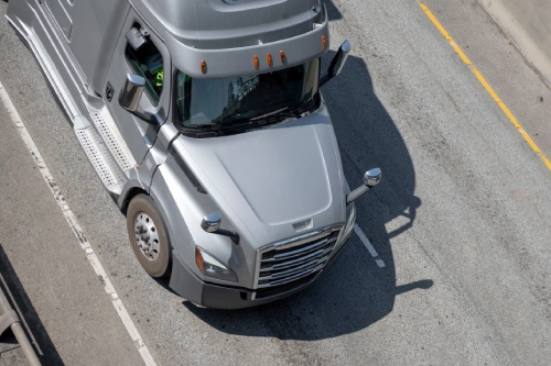 An overhead view of a grey truck driving along a major highway.