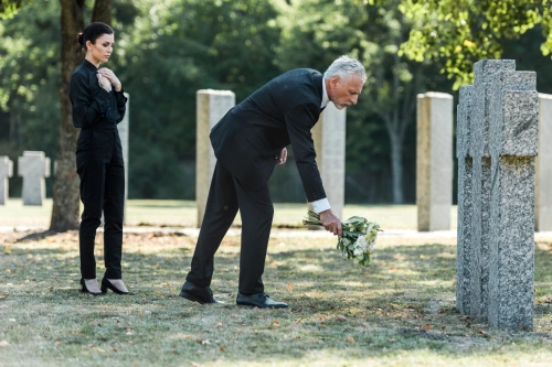 Two people leaving behind flowers at the grave of a deceased accident victim.