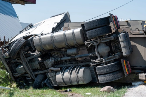 A large truck turned over on its side after an accident on a highway.
