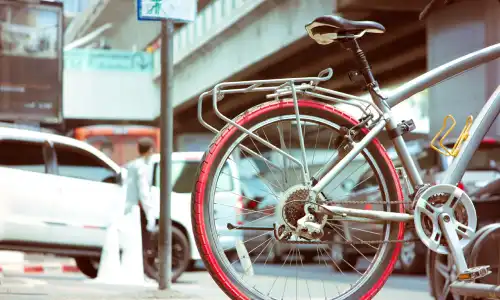 A partial shot of a bicycle at the side of a busy city street with vehicles in the background.