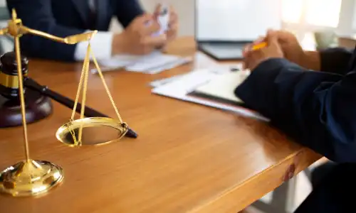 A lawyer talking with a client at their desk regarding a defective product case.