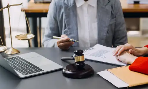 A lawyer holding a pen while going over a client's insurance policy together with them.