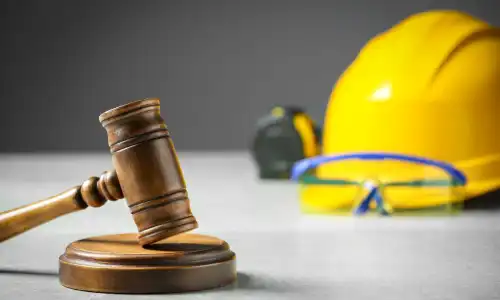 A gavel resting on a soundblock and with an out of focus helmet and tape measure in the background.