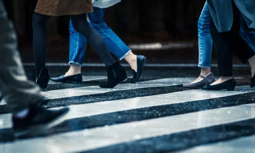 Pedestrians walking on a wet crosswalk on a rainy afternoon in the city.