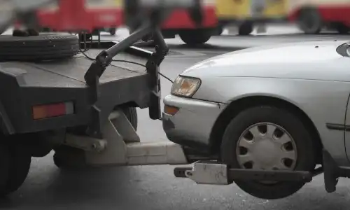 A tow truck pulling a grey sedan after it got into a collision with a hit and run driver.