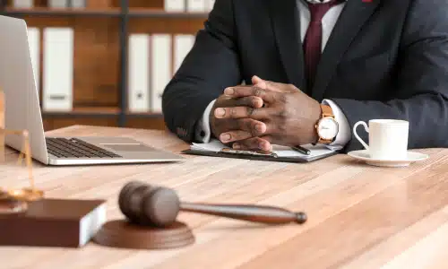 A bus accident lawyer seated behind his desk with his hands clasped as he awaits a client.