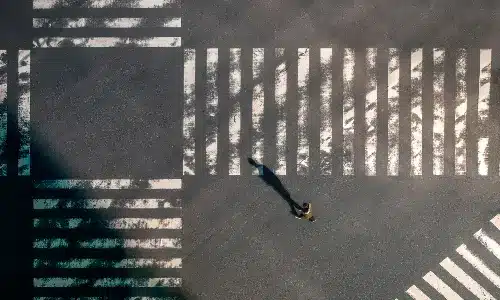 An overhead shot of a lone pedestrian going across a busy intersection at daytime.