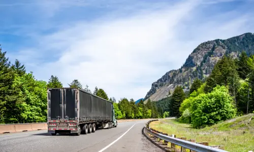 A truck traveling along an interstate highway pulling a large trailer.