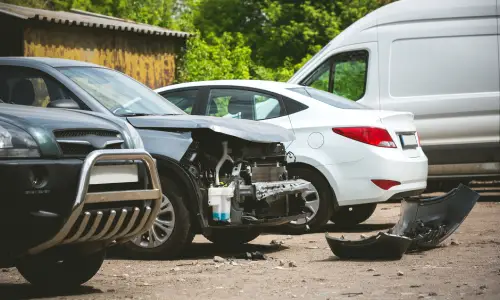 A car parked next to other vehicles after sustaining damage from an uninsured driver.