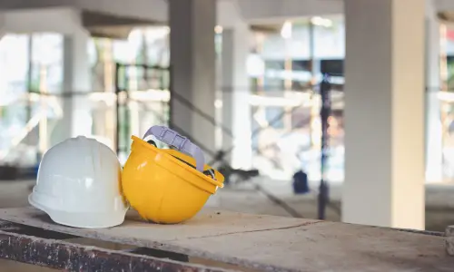 Two safety helmets on a makeshift table in a building's construction zone.