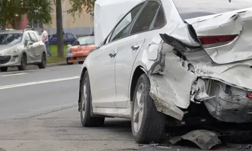 A white car with a totaled trunk after being rear-ended by a hit-and-run driver.