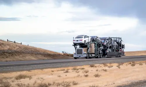 A large semi truck transporting multiple vehicles on an interstate highway at day.