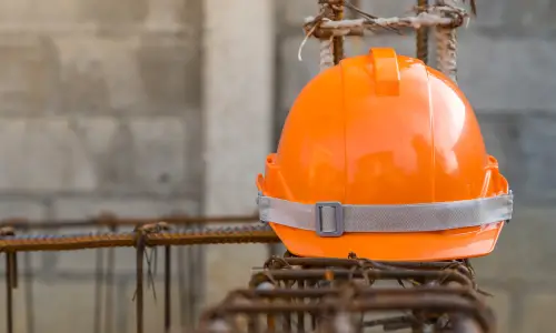 A construction helmet resting on some rebar and concrete at a construction site.