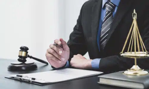 A slip and fall accident lawyer holding a pen in hand and seated behind his desk.