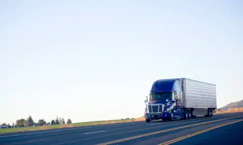 A large semi truck driving cargo along a national highway.