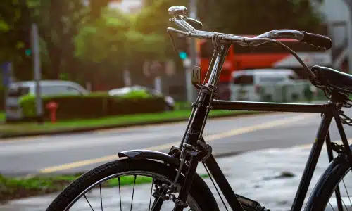 A black bicycle standing on the side of the road in a suburban neighborhood.