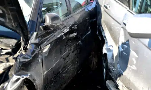 A collision between two cars in the middle of a city road in the daytime.