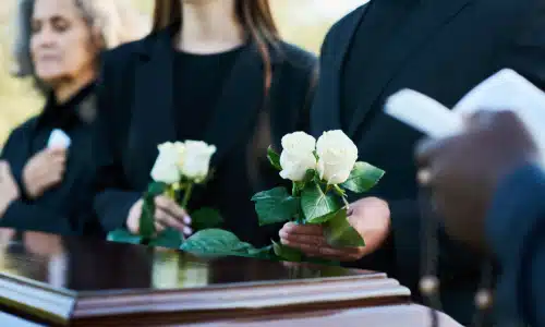 People mourning the loss of a loved one and gathered around a casket at a funeral.