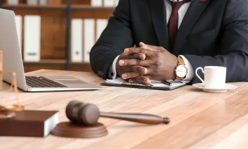 A boating accident lawyer with hands clasped and resting at his desk next to his laptop.