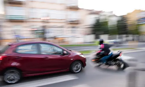 A motorcycle swerving in front of a car about to end up in an accidental collision.