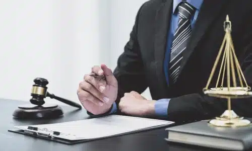 A medical malpractice lawyer sitting behind a desk and holding up a pen while waiting for a client.