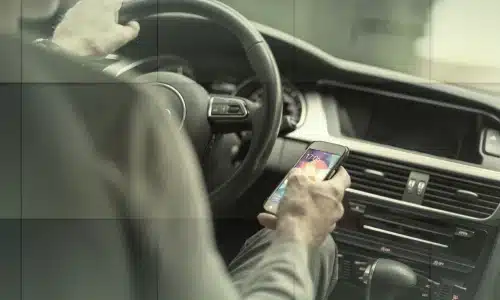 A distracted driver texting with eyes focused on their phone instead of on the road.