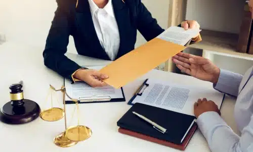 A personal injury lawyer pulling out documents from an envelope and handing them to a client.