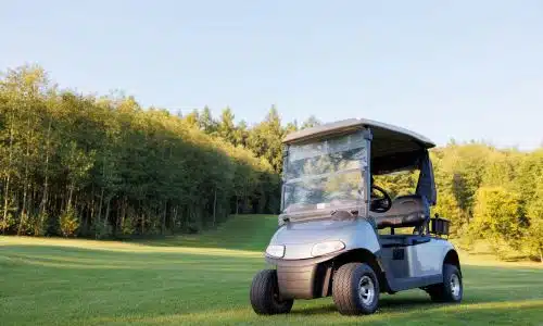 A golf cart sitting abandoned in the middle of a golf course fairway.