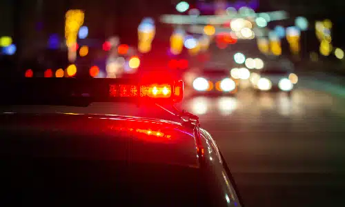A closeup rear shot of a police vehicle driving at night with flashers on.