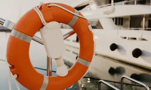 An orange lifesaver mounted at the docks next to a boat.