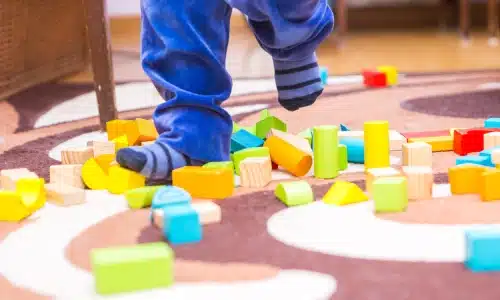 A child's feet as they walk on scattered toys at a daycare center.