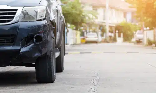 A black SUV at the side of a suburban road after being struck in a hit and run.