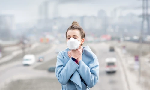 A woman wearing a mask and holding her throat, representing the health struggles of those affected by the chemical fire and seeking compensation through the BioLab class action lawsuit