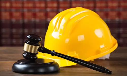 A safety helmet and gavel on a desk in front of law books.