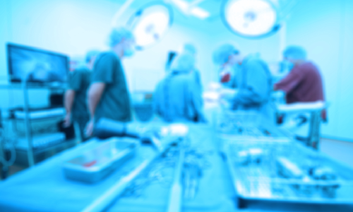 A team of doctors in an operating theater performing surgery on a patient in the background.