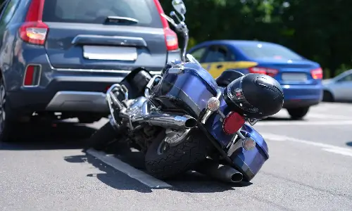 A large motorcycle without its rider tipped to its side after colliding with am SUV.