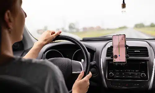 A rideshare driver looking at her GPS while driving her car.