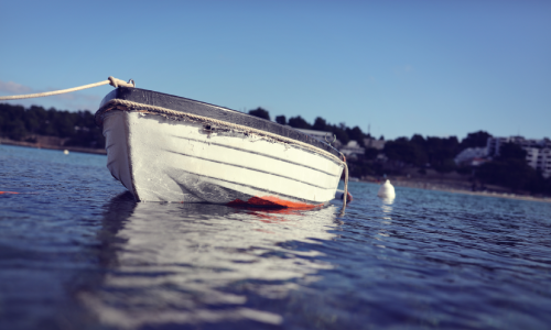 A low shot of a boat in the water and fastened with a rope.