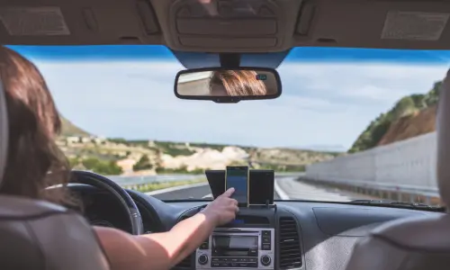 A rideshare driver adjusting her gps while on the highway.