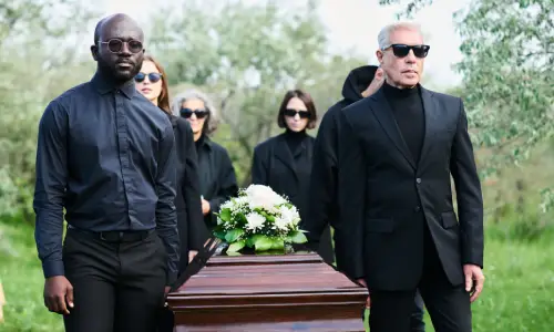 People at a funeral of a wrongful death victim lifting the casket at the cemetery.