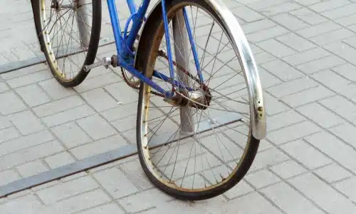 A blue bicycle with a bent front wheel after an accident on the road.