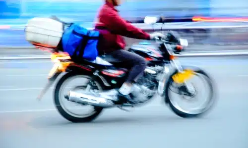 A blurred photo of a motorcycle driving along a city road.