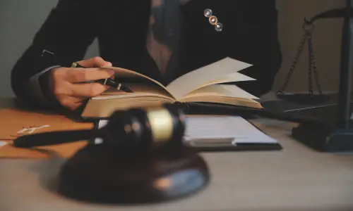 A defective product lawyer preparing for a case by reading through a law book at his desk.