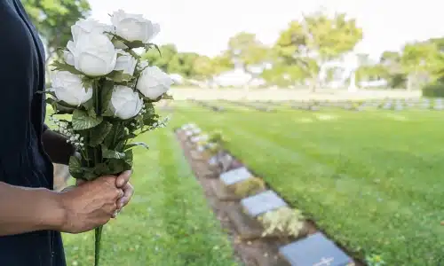 A person holding a bouquet of flowers to visit the grave of a wrongful death victim.